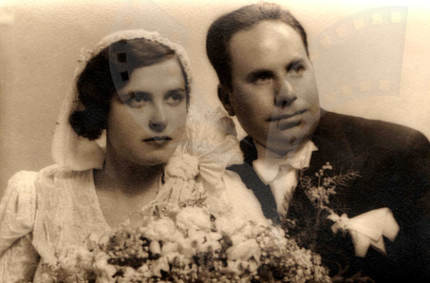 Ein Mann und eine Frau in festlicher Kleidung stehen nebeneinander und strahlen glücklich auf ihrer Hochzeit, während die Frau einen Blumenstrauß hält.