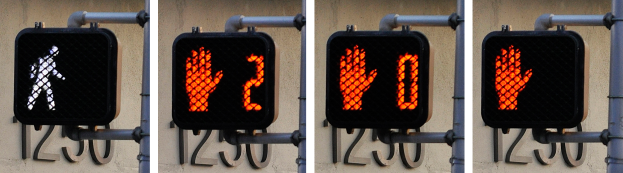 Eine Ampel mit drei Abschnitten, die jeweils ein anderes Signal anzeigen, an der Seite eines Gebäudes befestigt.