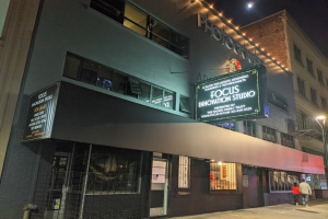 Das Focus Innovation Studio in New York City bei Nacht, mit beleuchteten Gebäuden, Menschen auf dem Gehweg und dem Himmel im Hintergrund.