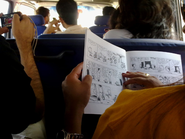 Eine Innenansicht eines Fahrzeugs, das Menschen in Kleidung, eine Armbanduhr, einen Fingerring, ein Buch und ein Gerät zeigt.