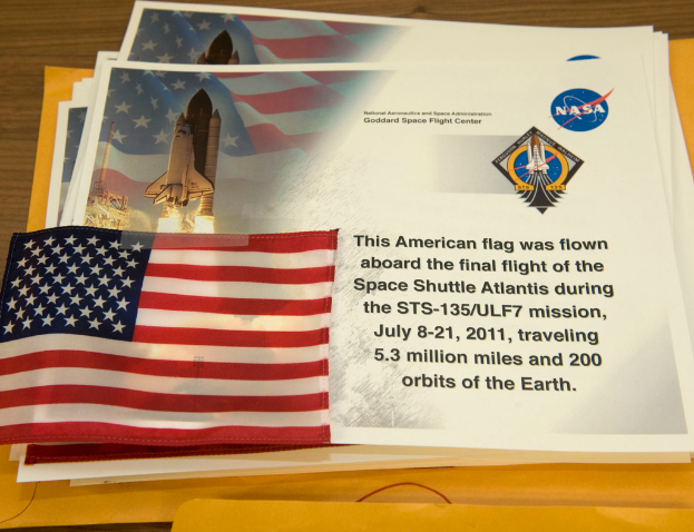 Plakate mit Text, einer Flagge, einer Rakete und Logos werden in der Mitte angezeigt, mit einem Tisch unten und einem Boden oben im Bild.