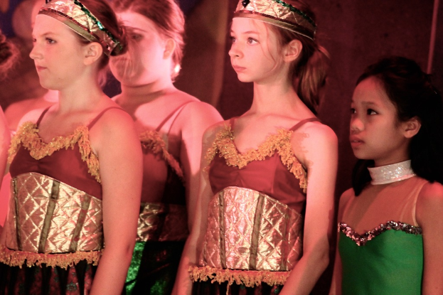 Mädchen in der Mitte, kostümiert und mit Kronen bekleidet.