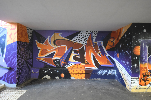 Graffiti-Mural an einer Gebäudewand mit farbenfrohen abstrakten Formen und Mustern.