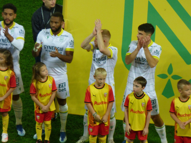 Eine Gruppe von Fußballspielern in Uniform klatscht auf einem Ligue-1-Feld.