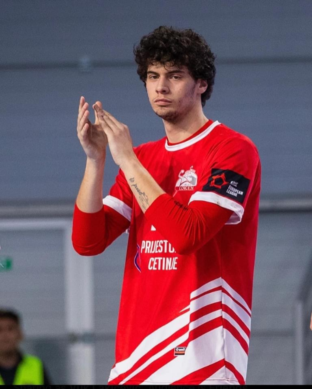 Ein Mann in rot-weißem T-Shirt klatscht in den Händen vorne, mit einer anderen Person und einer Wand im Hintergrund, und Text unten lesend "Copenhagen Futsal Club - Foto 1".