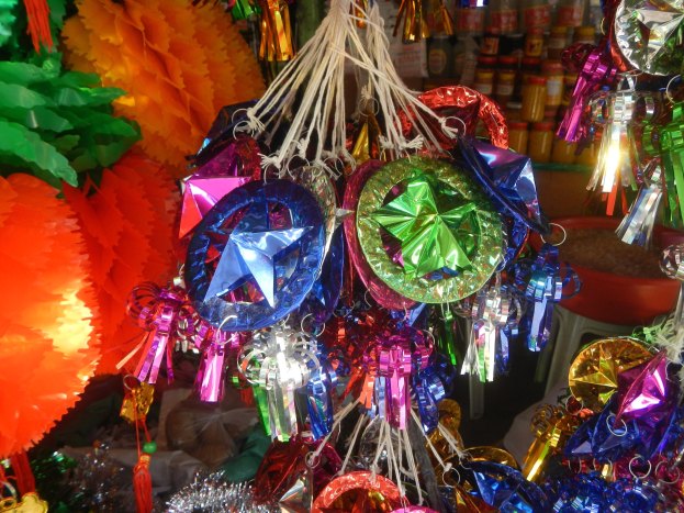 Eine festliche Decken-Dekoration mit farbigen Papierlaternen, Bändern und Dekorationen, mit Flaschen auf Regalen im Hintergrund.