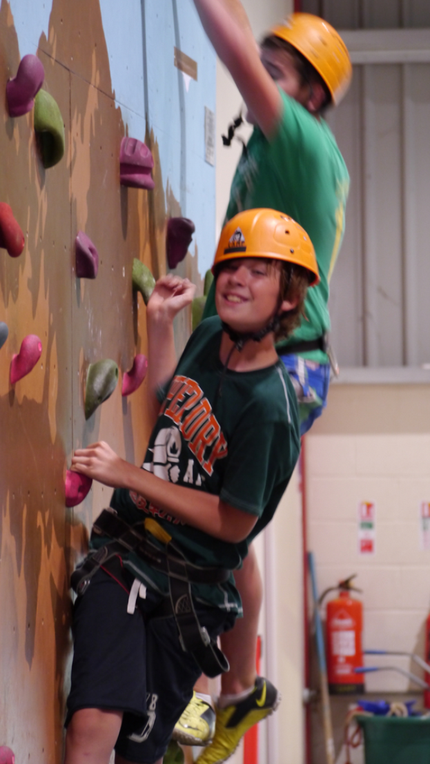 Eine Person klettert an einer Wand hoch, neben ihr befindet sich ein Feuerlöscher.