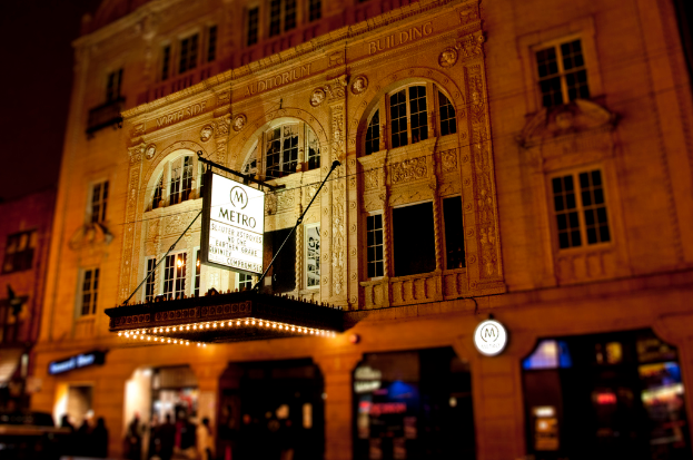 Ein gelbes Gebäude mit Geschäften im Erdgeschoss, von denen eines ein weißes Schild mit der Aufschrift 'Metro' trägt.