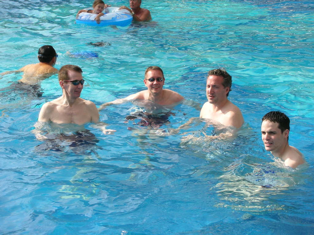 Mehrere Männer schwimmen im Wasser, während ein Mädchen mit einem Ballon schwimmt, den ein anderer hält.