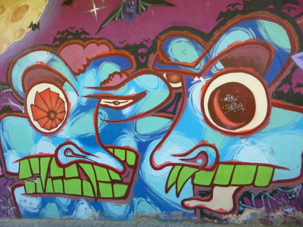 Ein leuchtendes, farbenfrohes Wandgemälde mit Graffiti-Kunst, das die Seite eines Gebäudes bedeckt und verschiedene Formen und Farben zeigt.