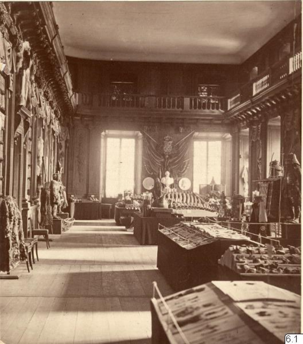 Schwarzes und weißes Foto eines Raums im Museum of Fine Arts, London, mit Tischen, Stühlen, Skulpturen an den Wänden, Fenstern, Vorhängen und Geländern.