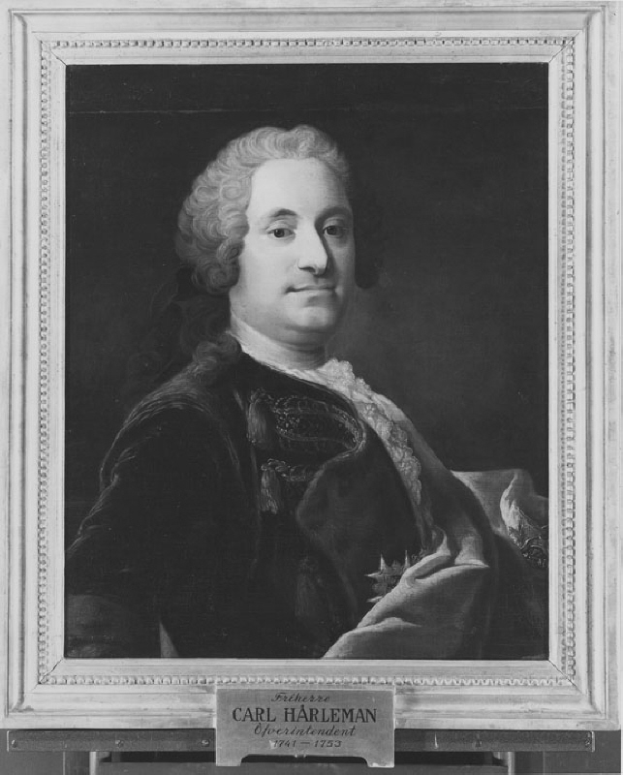 Ein Schwarz-Wei├č-Portr├Ąt eines Mannes mit ernstem Gesichtsausdruck, der einen langen dunklen Mantel mit hohem Kragen und Manschetten tr├Ągt und die H├Ąnde vor der Brust verschr├Ąnkt hat, dunkles Haar und konzentrierte Augen.