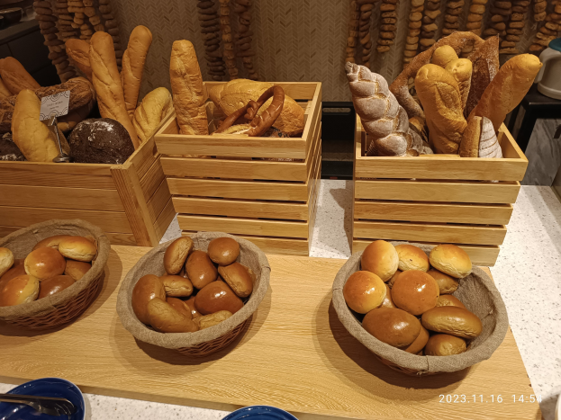 Holztisch mit Körben voller Brot, Tellern und Löffeln in einer Pariser Bäckerei.