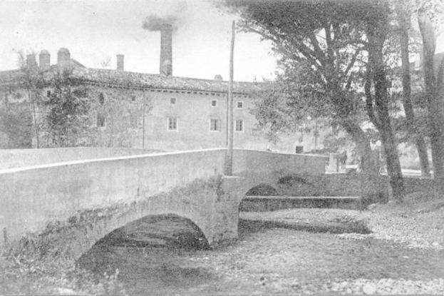 Eine Stadtansicht mit Gebäuden, Bäumen und einer Brücke im Vordergrund, Rauch aus einem Schornstein, unter einem Himmel mit Wasser am Boden.