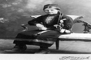 Ein altes Schwarz-Weiß-Foto einer Frau in traditioneller Kleidung, die friedlich mit geschlossenen Augen und auf dem Schoß ruhenden Händen dasitzt, mit einem unscharfen, träumerischen Hintergrund.