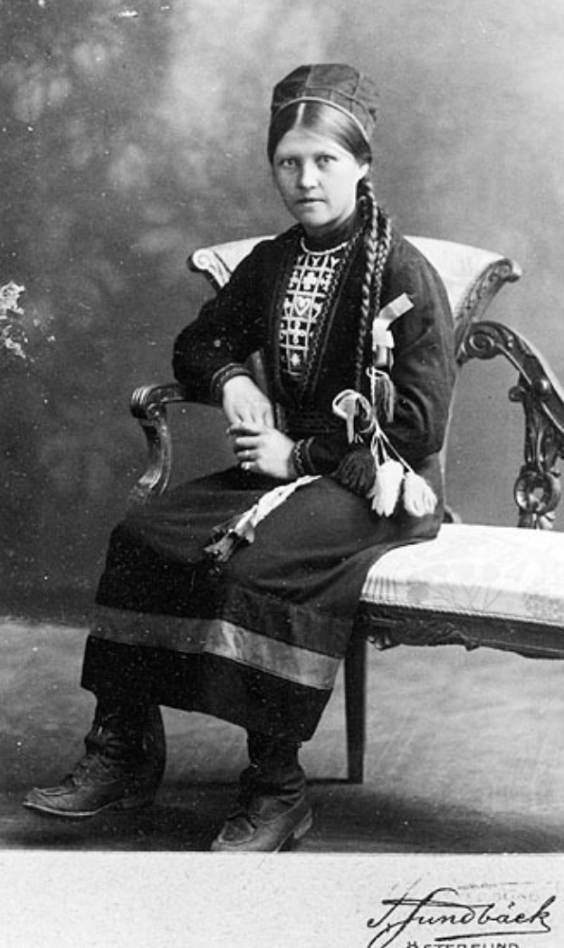 Ein altes Schwarz-Weiß-Foto einer Frau in traditioneller Kleidung, die friedlich mit geschlossenen Augen und auf dem Schoß ruhenden Händen dasitzt, mit einem unscharfen, träumerischen Hintergrund.