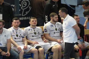 Eine Gruppe von Männern sitzt auf einer Bank, einige halten Flaschen, mit einem Banner im Hintergrund mit der Aufschrift "Nordkraque vs Bordeaux."