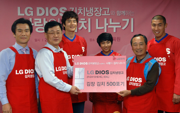 Eine Gruppe von Männern hält gemeinsam eine große LG-Firmenkarte mit einem Banner im Hintergrund.