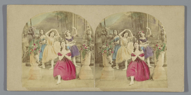 Ein Schwarz-Weiß-Foto von Frauen in pinken Kleidern, die auf einer geschmückten Bühne tanzen, mit erhobenen Armen und Blumenvasen und üppigen grünen Bäumen im Hintergrund.