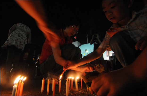 Mehrere Personen zünden Kerzen in einer Gruppe an.