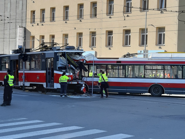 Rote und weiße Straßenbahn krachte an der Seite der Straße mit Menschen in der Nähe und einem Gebäude im Hintergrund.