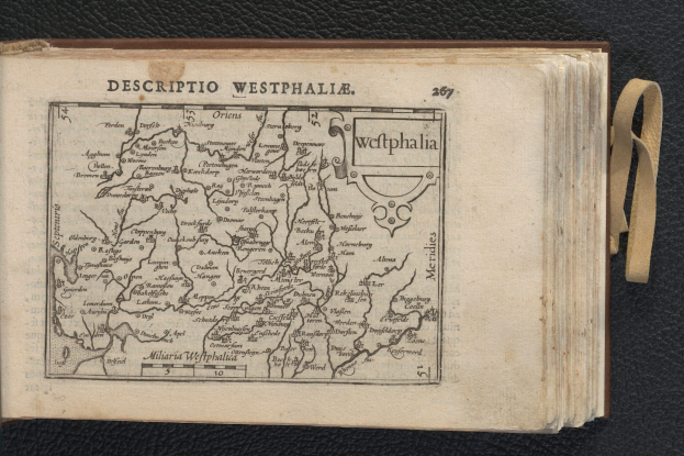 Ein aufgeschlagenes Buch mit einer detaillierten Karte von Westphalien darauf, das auf einer schwarzen Oberfläche liegt.