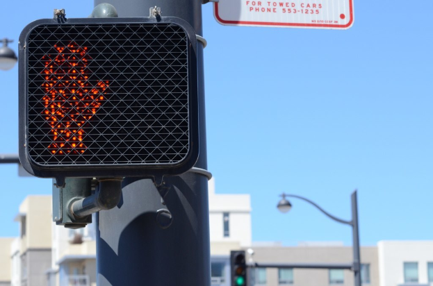 Eine Straßenszene mit Verkehrspfählen, Ampeln, Straßenlaternen, Gebäuden und einem klaren Himmel.
