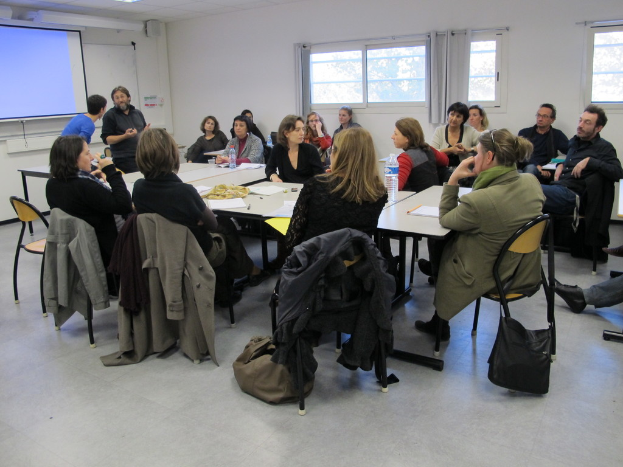 Eine Gruppe von Menschen, die sich unterhält und diskutiert, mit zwei Personen im Hintergrund, die miteinander sprechen.