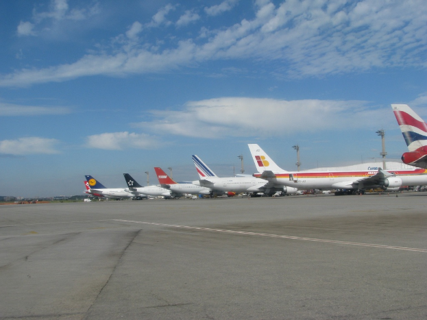 Eine Start- und Landebahn mit einigen Flugzeugen, Pfosten, Kabeln und einer bewölkten Himmel.