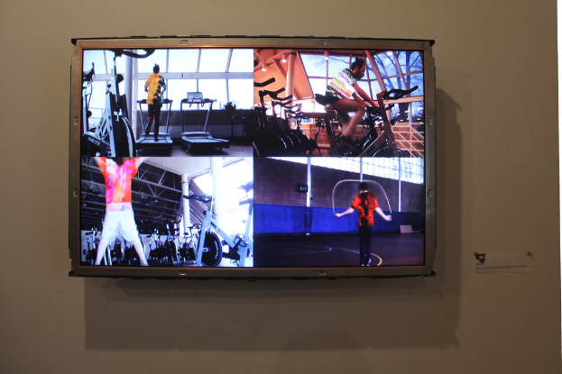 Ein an der Wand befestigter Fernseher mit Menschen, die darauf Sport treiben.