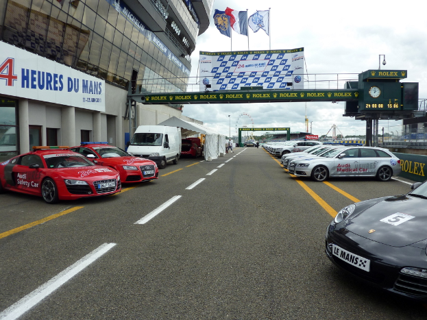 Autos parken vor einem Gebäude auf der rechten Seite, mit Bannern auf der rechten Seite.