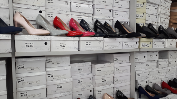 Ein Regal mit verschiedenen Schuhen in Kartons mit Preisschildern, mit Kartonagen auf der rechten Seite.