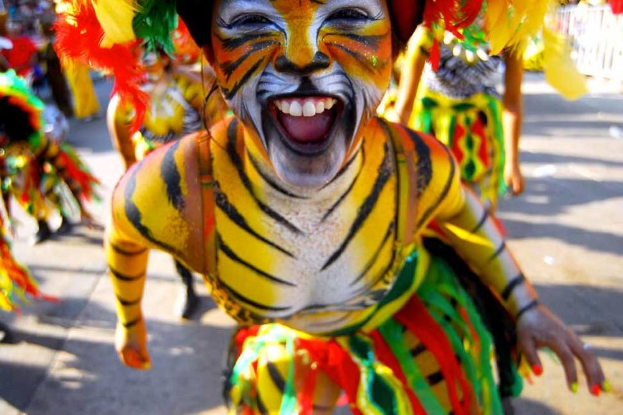 Eine Gruppe von Menschen in bunten Kostümen und Schminke, mit einer Frau in einem Tigerkostüm, auf einem Karneval, mit einem unscharfen Hintergrund.