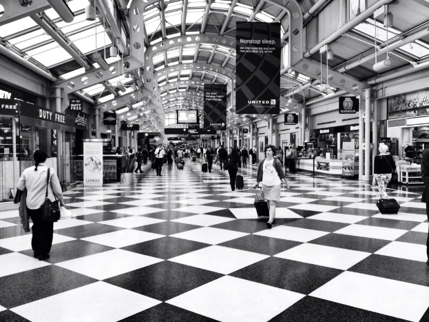 Menschen mit Taschen gehen in einem Gebäude mit Geschäften und Bannern.