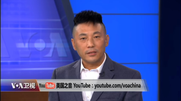 Ein Mann im Anzug und Krawatte auf einem TV-Bildschirm mit blauem Hintergrund, identifiziert als chinesischer Nachrichtensprecher durch den Text unten.