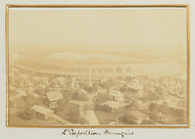 Altes Schwarz-Weiß-Foto eines Stadions in städtischer Umgebung mit umliegenden Gebäuden, Bäumen und Strommasten, mit lesbarem Text unten.