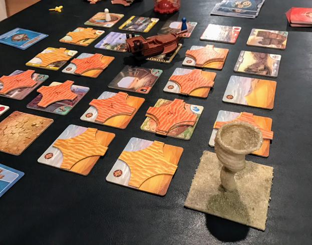 Ein Tisch voller Star Wars: The Old Republic-Brettspielkarten, Spielzeuge und andere Gegenstände in einem Raum mit einer Wand im Hintergrund.