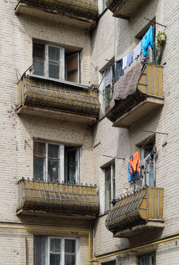 Ein Wohnhaus mit Fenstern, Balkonen und Wäsche, die zum Trocknen aufgehängt ist, mit Rohren an der Seite.