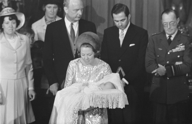 Königin Elizabeth II. hält ihren neugeborenen Sohn, Prinz Philip, während Prinz Philip, Herzog von Edinburgh, neben ihr in einem Anzug und Krawatte steht, mit Vorhängen im Hintergrund.