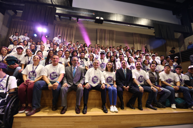 Eine Gruppe von Menschen sitzt auf einer Bühne mit einer Person im Rollstuhl links, mit Vorhängen, Scheinwerfern und einer Wand im Hintergrund bei der Nationalen Konferenz der Frauen-Basketball-Vereinigung.
