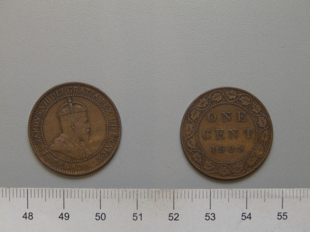 Zwei Ein-Cent-Münzen nebeneinander auf einem Lineal auf einer weißen Oberfläche.