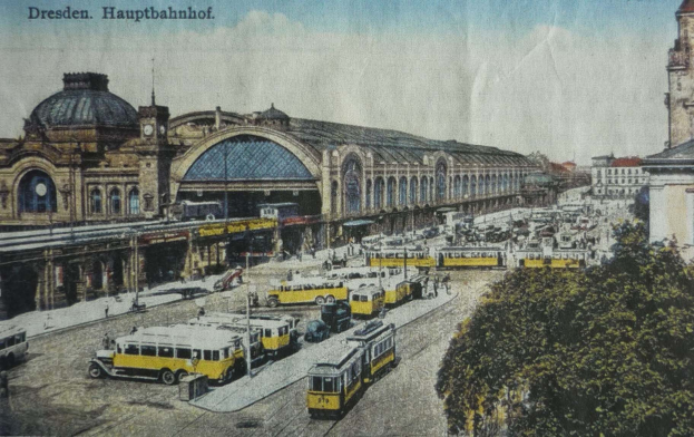 Alte Postkarte des Dresdner Hauptbahnhof Bahnhofs in Deutschland, die eine belebte StraßenSzene mit Fahrzeugen, Fußgängern, Bäumen, Gebäuden und einem bewölkten Himmel zeigt.